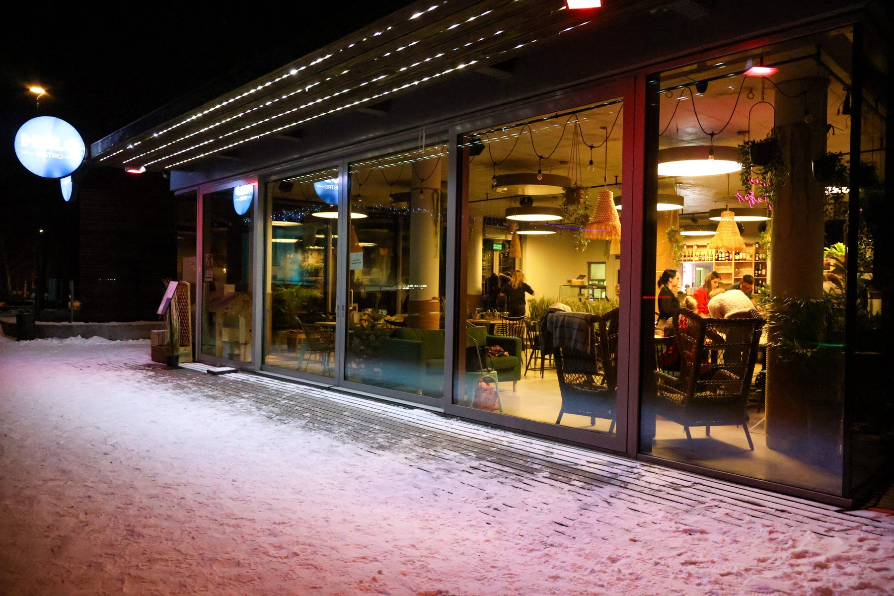MOLO Bistro nocą — różowe światło i niebieski szyld nad plażą Ukiel